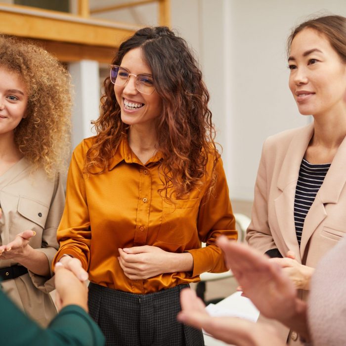 Group of friendly women clapping hands and congratulating their colleague on getting career promotion